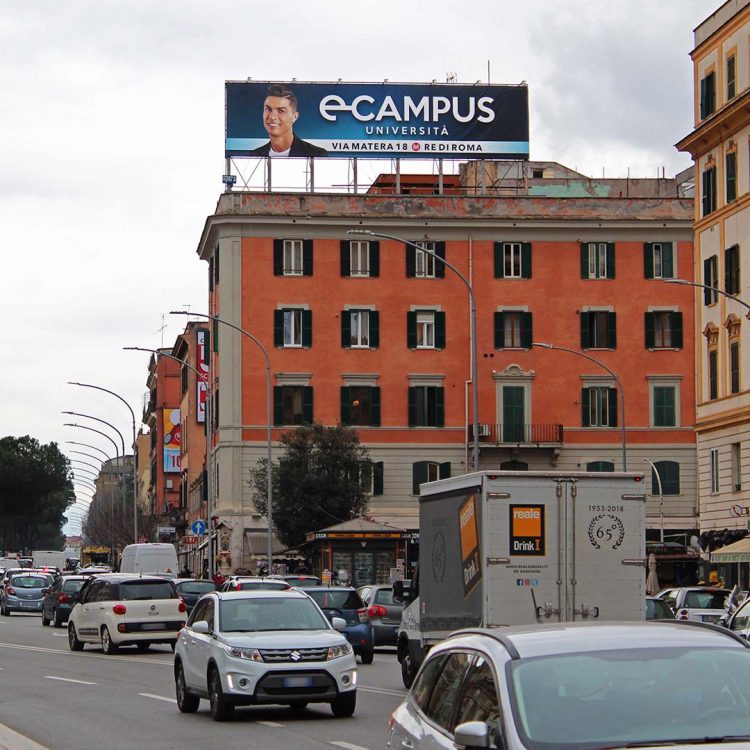 Maxi affissione in Piazza dell'Alberone a Roma, su tetto di un palazzo frontale al traffico.